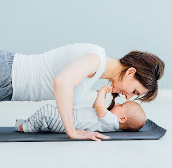 young mother does physical yoga exercises together with her baby boy